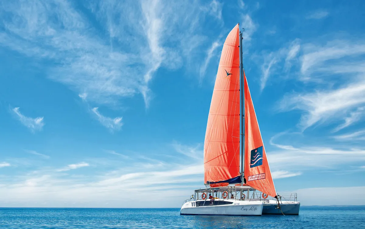 Парусный катамаран Catamaran VN с оранжевыми парусами в открытом море у Нячанга
