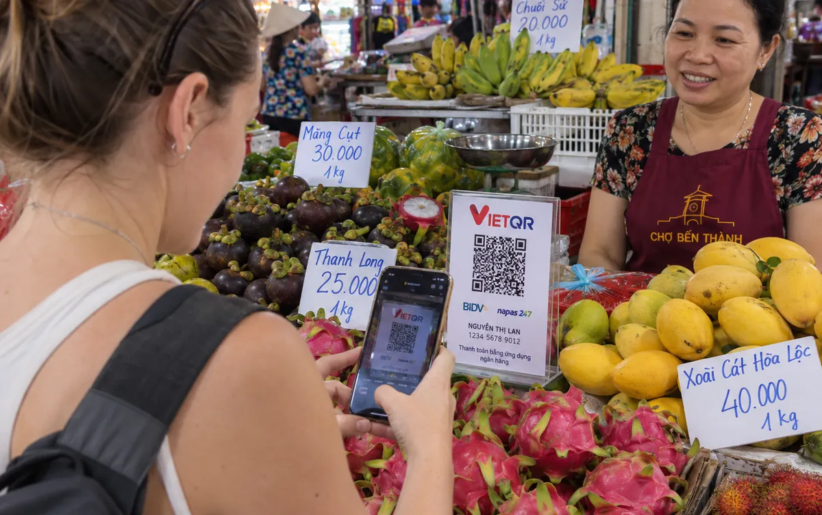 Покупатель оплачивает фрукты по QR-коду телефоном на рынке в Нячанге